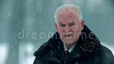 一位年迈的祖父-头发灰白、头秃的祖父正站在外面下雪
